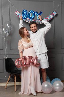 Cinsiyet ayrımcılığı sırasında yazıt tutan bir çiftin tam boy görüntüsü balonların üzerinde parti olduğunu gösteriyor..