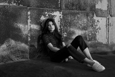 Moda görünümlü, düz saçlı, kameraya bakıp sigara içen genç bir kızın önden görünüşü..