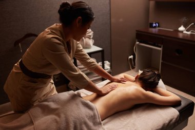 Sırt masajı yaptıran genç bir kadının arka plan görüntüsü. Spa konsepti.