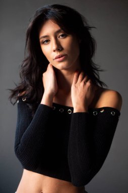 Stüdyoda gri arka planda poz veren seksi esmer bir kadının yakın plan profili..