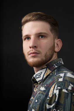 Stüdyoda poz veren gömlekli yakışıklı bir adam. Moda tarzı olan çekici bir adam. Kendine güvenen bir adam. Kahverengi saçlı, soyutlanmış siyah arka planlı yetişkin çocuk..