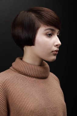 Mutsuz, üzgün, üzgün, ciddi bir kızın yakın plan portresi kahverengi süveter giyiyor, gri arka planda soyutlanıyor.