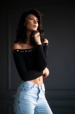 Stüdyoda gri arka planda poz veren seksi esmer bir kadının profili..