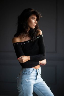 Stüdyoda gri arka planda poz veren çekici esmer kadın..