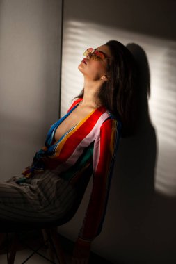 Renkli bluz ve güneş gözlüğü takmış zarif bir genç kadının profil portresi..