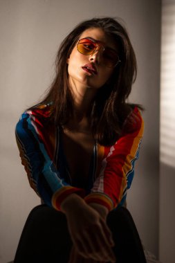 Renkli bluz ve güneş gözlüğü takmış genç ve zarif bir kadının ön portresi..
