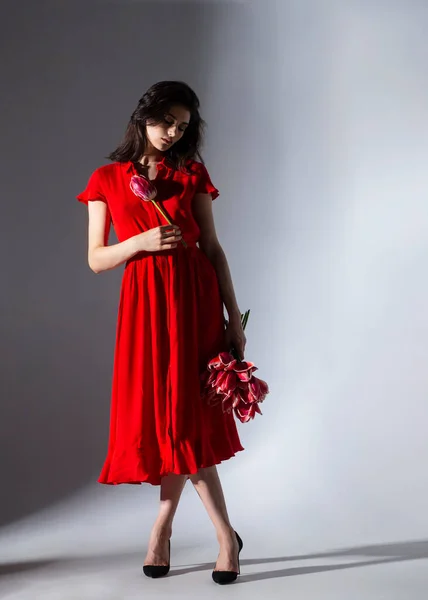 Elegante Morena Joven Vestido Rojo Sosteniendo Unos Hermosos Tulipanes Rojos — Foto de Stock