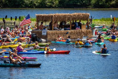 Wausau, Wisconsin, USA, July, 30, 2022: 8th Annual Paddle Pub Crawl on Lake Wausau and the Wisconsin River, Kayakers enjoying the band Feed the Dog and Ed Giallomardo playing the bagpipes, horizontal