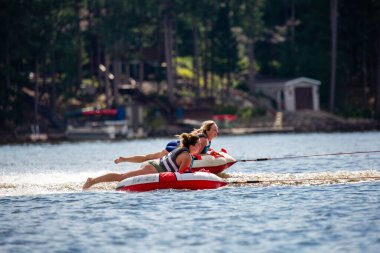 Nokomis Gölü, Tomahawk, Wisconsin, ABD, 20 Ağustos 2022 - Kızlar şişme bir tüple göl boyunca çekiliyor,