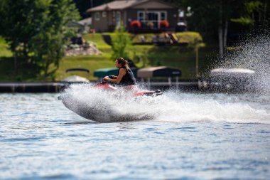 Nokomis Gölü, Tomahawk, Wisconsin, ABD, 20 Ağustos 2022 - Gölde uçan jet ski üzerindeki kız, yatay
