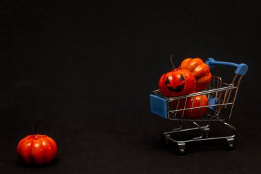 Arabadaki turuncu balkabakları ve siyah arka planda dağınık balkabakları. Cadılar Bayramı 'nda satıştan bahseden yassı lei. Boşluğu kopyala.