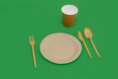 Yeşil arka planda geri dönüşümlü çatal, kaşık, bıçak, tabak ve bardak. Mutfak aletleri. Üst Manzara. Minimalist stil. Boşluğu kopyala.