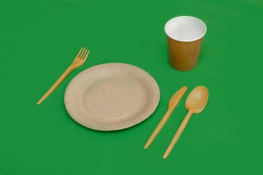 Yeşil arka planda geri dönüşümlü çatal, kaşık, bıçak, tabak ve bardak. Mutfak aletleri. Üst Manzara. Minimalist stil. Boşluğu kopyala.