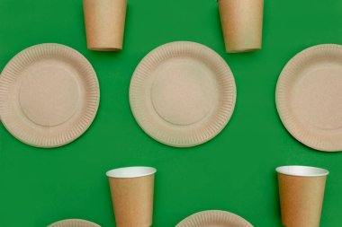 Kağıt tabak, yeşil arka planda cam. Çevre dostu, gübrelenebilir, tek kullanımlık, geri dönüşümlü malzemeler. Sıfır plastik, gezegeni kurtarmak, plastiği durdurmak. Atık geri dönüşümü kavramı.