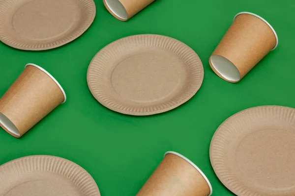 Paper plate, glass on a green background. Eco-friendly, compostable dishes, disposable, recyclable materials. Zero plastic, saving the planet, stop plastic. The concept of waste recycling.