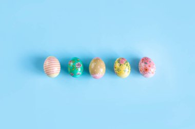 Renkli, Paskalya için boyanmış, tavuk yumurtaları mavi arka planda yatıyor..