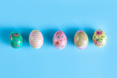 Renkli, Paskalya için boyanmış, tavuk yumurtaları mavi arka planda yatıyor..