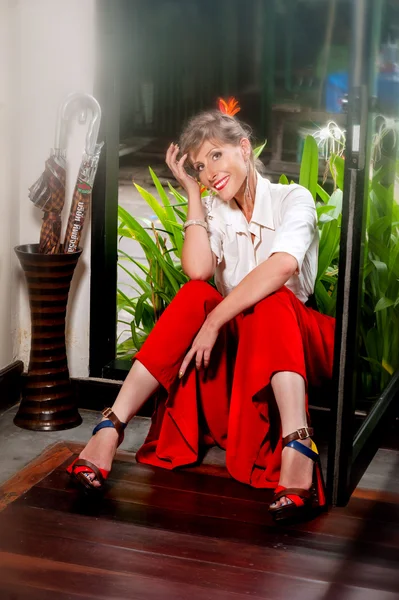 Balkonda oturan ve gülümseyen genç kadın