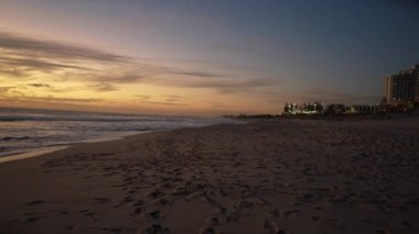 the beautiful purple waves of Scarborough beach at dusk with buildings in the background