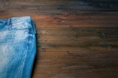 Kahverengi ahşap arka planda mavi kot pantolon. Sert bir tahta yüzeyde yıpranmış kot pantolon.