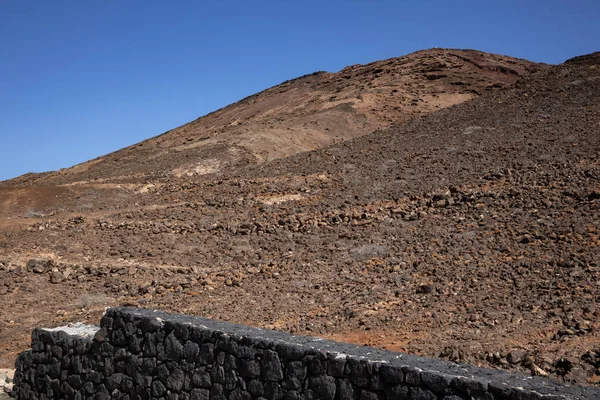 Sabah güneşinde lav dağı. Parlak mavi gökyüzü. Monatna Roja, Playa Blanca, Lanzarote, Las Palmas, Kanarya Adaları, İspanya.
