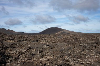 Area of a Timanfaya National Park, very important touristic place at the island, preserving the heritage of a volcanic activity. Blue sky with white clouds. Lanzarote, Canary Islands, Spain.