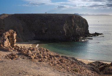 View from the mountain on Papagayo Beach. Atlantic ocean in a late afternoon light. Clouds on a blue sky in the early spring. Playa del Papagayo, Lanzarote, Canary Islands, Spain.