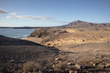 View from the mountain on Papagayo Beach. Atlantic ocean in a late afternoon light. Clouds on a blue sky in the early spring. Playa del Papagayo, Lanzarote, Canary Islands, Spain.