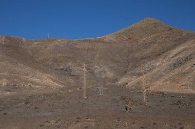 Volkanik kökenli çöl. Bir sürü taş, kaya ve bir tepe var. Mavi yay gökyüzü ve ışık bulutları. Lanzarote, Kanarya Adaları, İspanya.