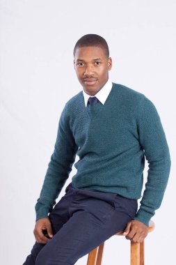 Yakışıklı siyah adam gülümseyerek oturuyor.