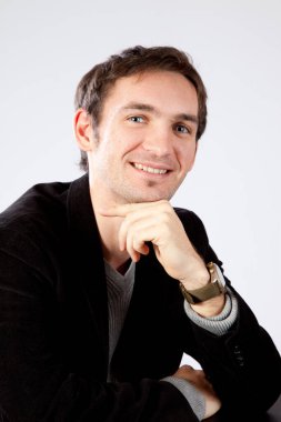 Yakışıklı adam gülümseyerek oturuyor.