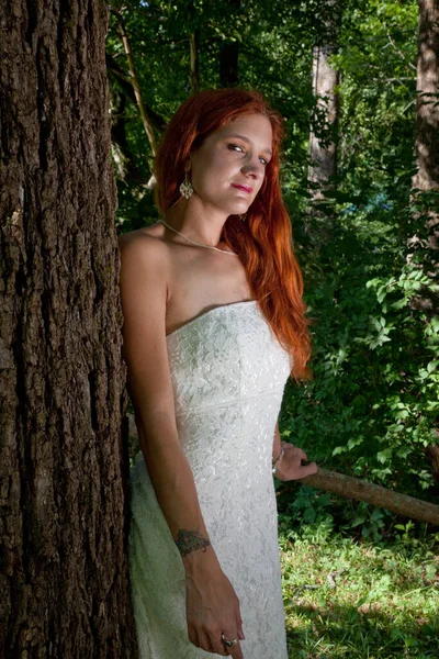 Lovely redhead outdoors in a wedding dress