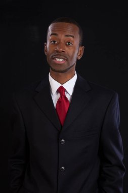 Takım elbiseli siyah bir işadamı düşünceli görünüyor.