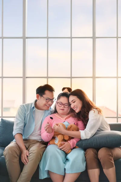 Happy asian family sitting on sofa and playing dolls with their daughter down syndrome child in living room at morning time, Activity happy family lifestyle concept,