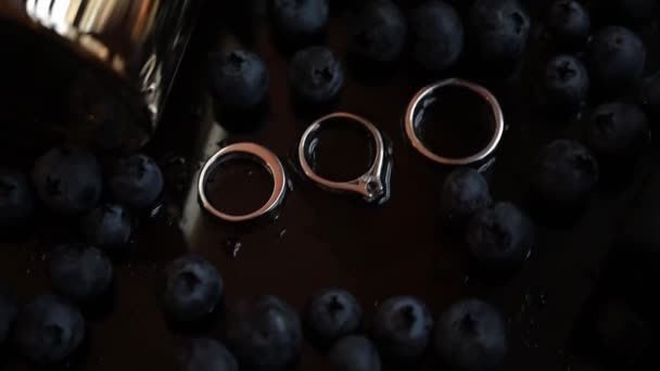 Trauringe Auf Blauem Hintergrund Großaufnahme Von Ringen Blaubeeren Damenschuhen Mit — Stockvideo