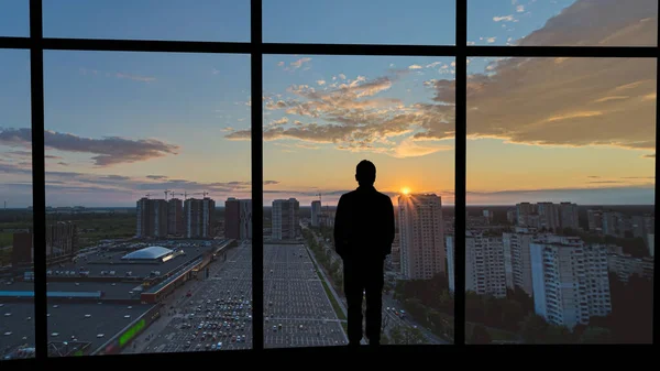 那个人站在大楼上 挡住了城市的日落 — 图库照片