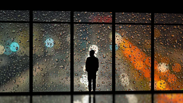 The man standing near the wet panoramic window
