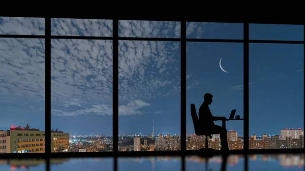 The businessman sitting near the panoramic window on the night city background