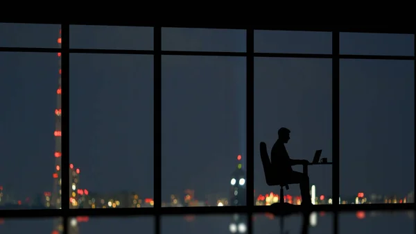 The man working near the panoramic window on the night city background