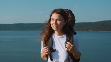 The beautiful woman walking with backpack along the coast