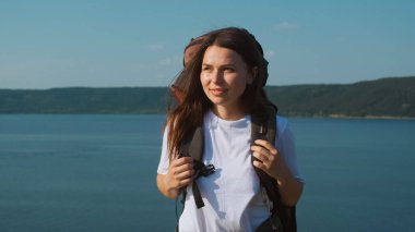 The beautiful woman walking with backpack along the coast