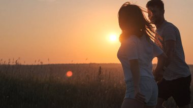 The romantic couple playing on mountain top on sunset background