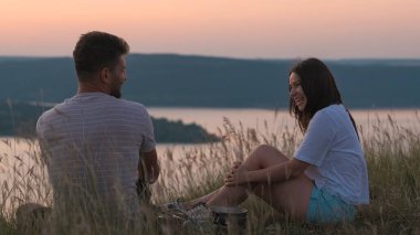 The happy couple sitting on mountain top and drinking tea