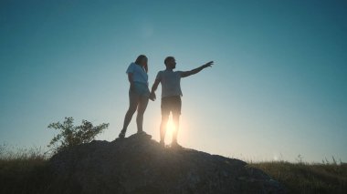 The young couple standing on a mountain top on a blue sky background
