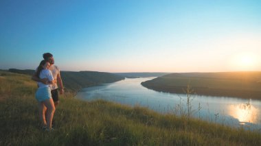 The romantic couple standing on a mountain top on a beautiful river background