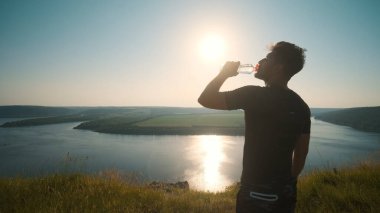 The man drinking water on a beautiful river background