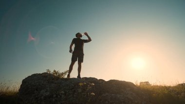 The man drinking water on a mountain top