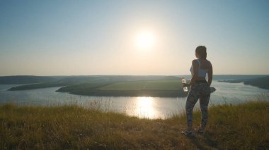 The sportive woman standing on a beautiful river background