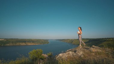 The sportive woman standing on a beautiful river background