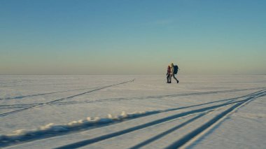 The two expeditors with backpacks walking through the snow field